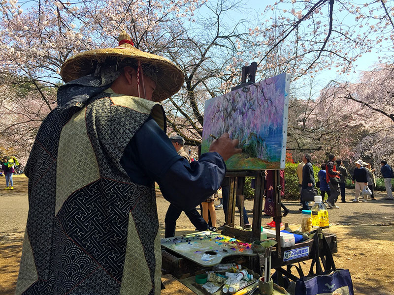 Một họa sỹ đang vẽ tranh tại một công viên Hoa Anh Đào, Nhật Bản